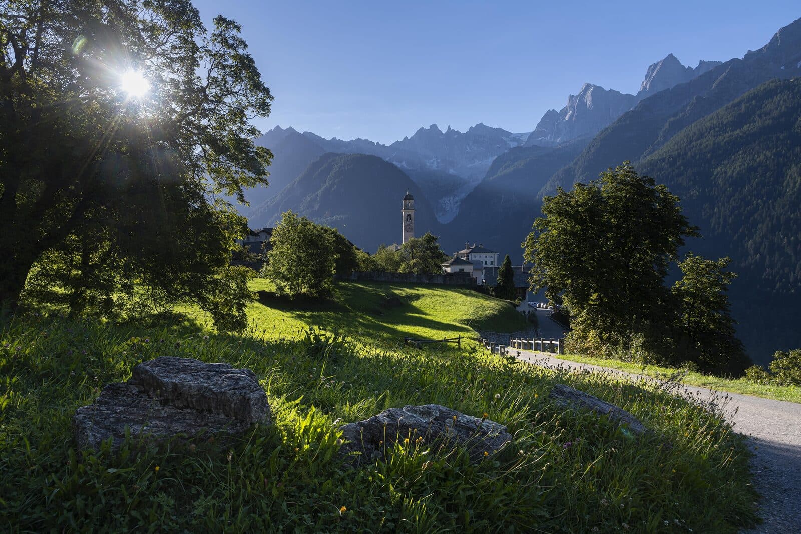 Ein hochalpines Tal mit einem Steindorf und schneebedeckten Gipfeln